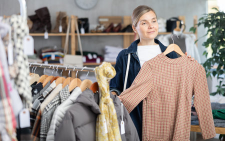 European woman near showcase pick out and buying warm dress