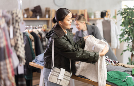 Adult woman chooses sweater in clothing storeの写真素材