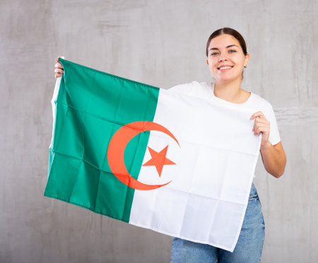 Happy girl stands with flag of Algeria .Isolated on gray backgroundの写真素材