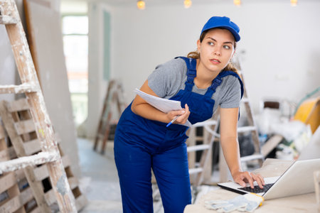 Woman worker checking documents and using laptop in construction siteの写真素材