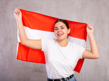 Smiling young female celebrating National Day while holding flag of Austriaの写真素材