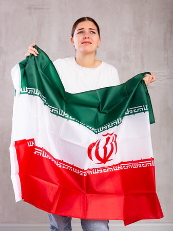 Unhappy girl holding the Iran flag in her hands.の写真素材