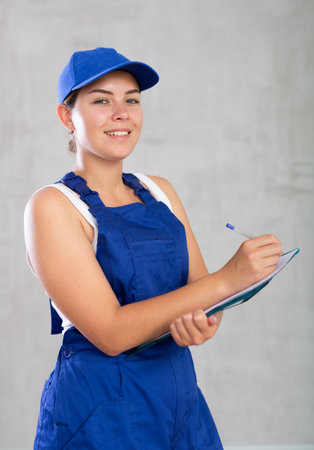 Young woman in work overalls making notesの写真素材
