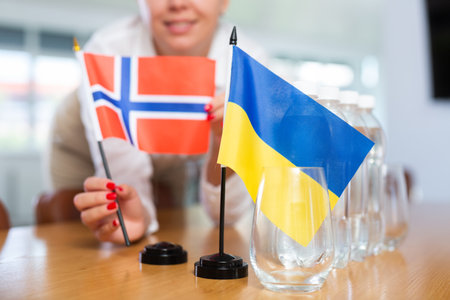 Unrecognizable girl sets midget flags of Ukraine and Norway before international negotiationsの写真素材