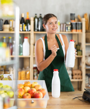 Young woman seller offering milk in grocery store