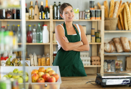 Young woman seller at counter in grocery storeの写真素材
