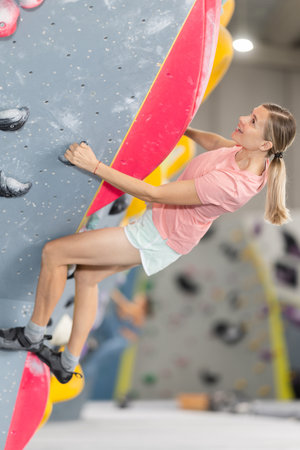 Woman doing difficult wall climb in climbing gymの写真素材