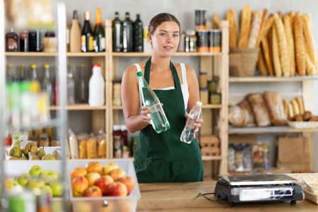 Young woman seller offering water in grocery store