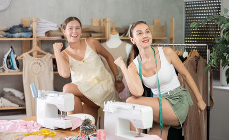 Two young seamstresses doing exercises during breakの写真素材