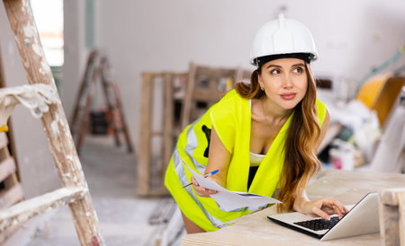 Woman in a vest makes checks repair plan on the laptop