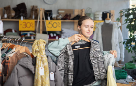 Elegance teenager girl choose something for autumn-winter season in clothing boutique. Sale of winter clothing collectionの写真素材