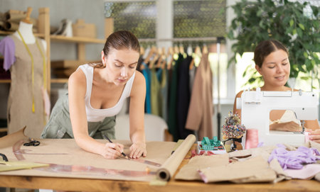 Woman sewing, female assistant drawing paper dress pattern by curvesの写真素材