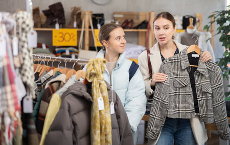 Adult woman and teenage girl choosing coat