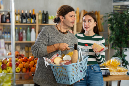 Married couple searches for fresh produce in the grocery section of supermarketの写真素材