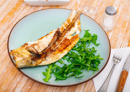 Grilled sea bass fish served with arugula