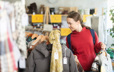 Teenage girl choosing something for autumn-winter in clothing storeの写真素材