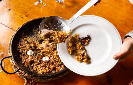 Customer pouring mountain rice with mushrooms and pork feet into plateの写真素材
