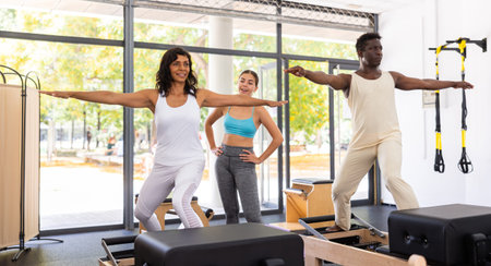 Multiracial people exercising pilates with trainer in gym