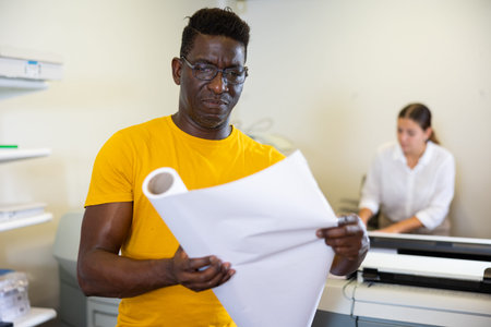 Middle-aged man holding large format paper in a roll in the middle of the typography