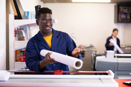 Portrait positive of man printshop worker with plotter paper roll