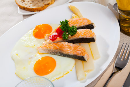 Fried salmon with scrambled eggs and asparagusの写真素材