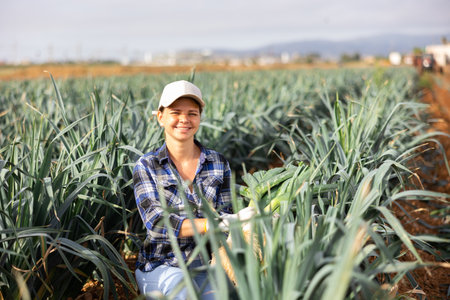 Woman farmer with leek in her hands on a farmer fieldの写真素材