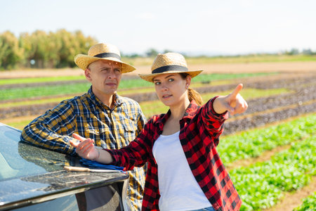 Farmers talking near car at farm fieldの写真素材
