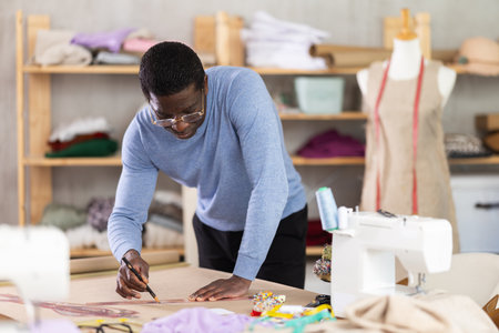 African American man tailor draw dress pattern of product on paperの写真素材