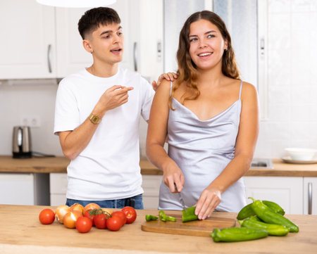 Woman preparing vegetable salad and communicating with her husband in kitchenの写真素材
