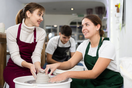 Two young women sculpt product on potters wheelの写真素材
