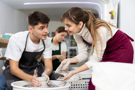 Man working with pottery wheel and master giving instructionsの写真素材