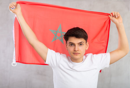 Focused young guy holding flag of Moroccoの写真素材