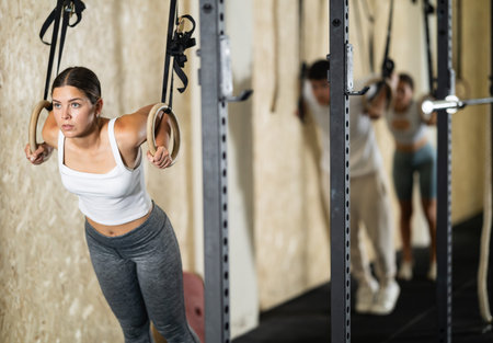 Girl trains on gymnastic rings in modern crossfit gym