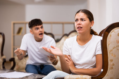 Portrait of sad woman in living room, while husband looks upsetの写真素材
