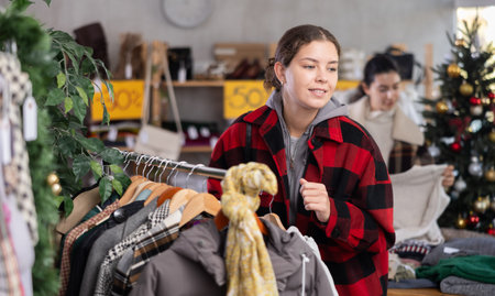 Young girl near showcase pick out and buying coat or jacket