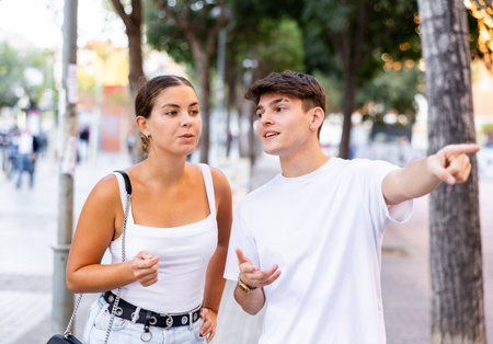 Positive tourist couple walking around foreign city on summer day, pointing at sightsの写真素材