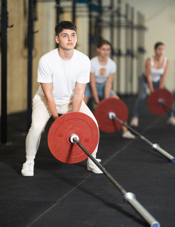 Young guy lifts barbell in gymの写真素材