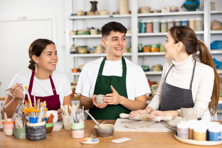 Joyous young man and women sculpting handmade cups