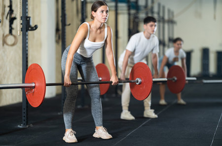 Young woman lifting barbell in gymの写真素材