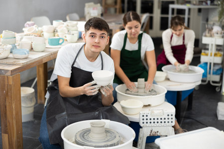 Young man holding clay bawl at pottery wheelの写真素材
