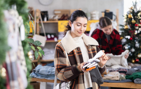 Armenian woman choosing a set of socks against the background of a Christmas tree in a storeの写真素材