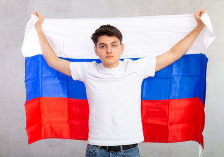 Focused young guy holding flag of Russiaの写真素材