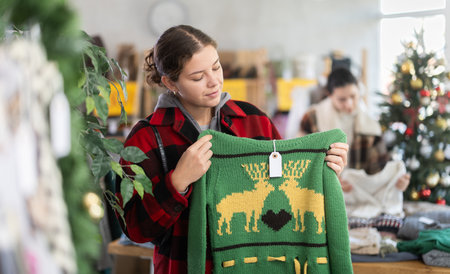 Uncertain young girl choosing sweater in clothing storeの写真素材