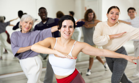 Cheerful young lady learning new modern dance in group dance lessonの写真素材