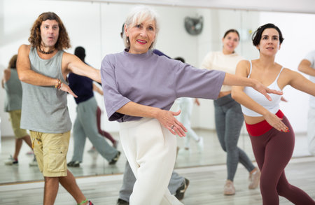 Mature woman rehearsing modern dance with group in dance schoolの写真素材