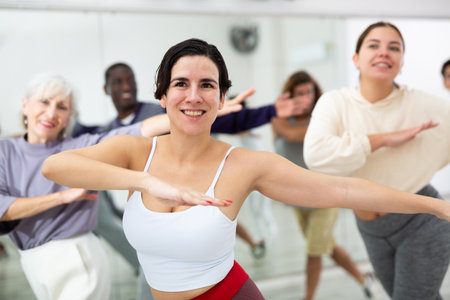 Cheerful young lady learning new modern dance in group dance lessonの写真素材
