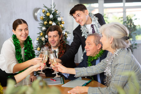 Cheerful young, adult, old office workers with glasses of champagne rejoicing together New Year party in company branchの写真素材