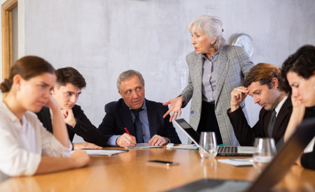 Irritated elderly female boss reprimanding subordinates in officeの写真素材