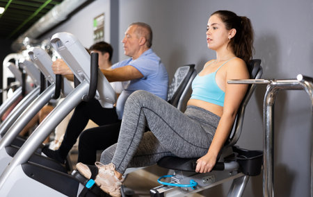 Young girl doing cardio training on stationary bike in gym