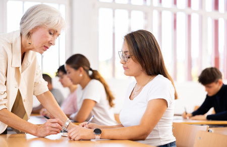 Senior woman teacher helping student with task solution